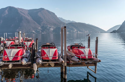 Deck chairs by lake against sky