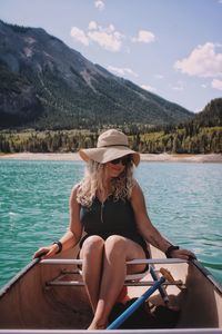 Woman sitting on boat in lake against mountains