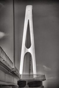 Low angle view of bridge by building against sky