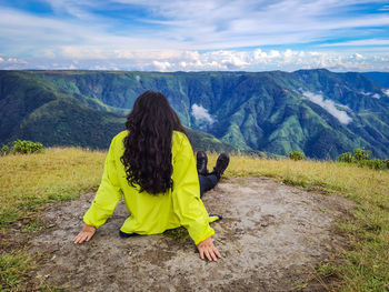 Young girl sitting on mountain top with bight blue sky at morning