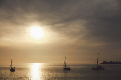 Silhouette sailboat sailing on sea against sky during sunset