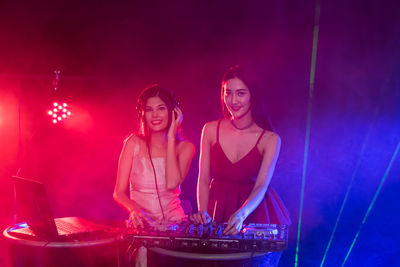 Happy women playing music in illuminated nightclub