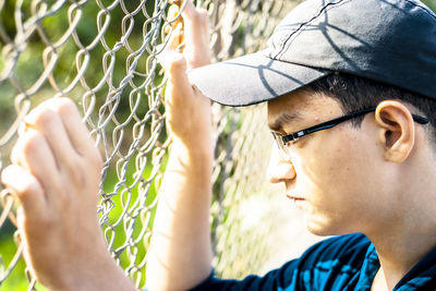 Close-up of thoughtful boy by fence