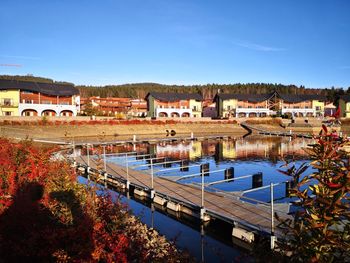 Scenic view of river by buildings against blue sky
