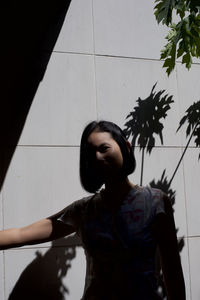 Young woman standing against wall