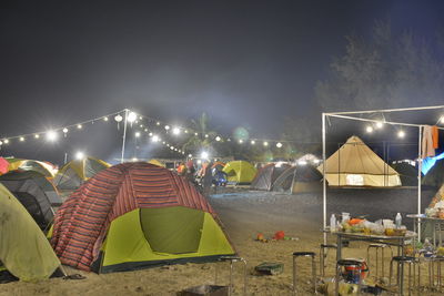 Illuminated street lights at beach against sky at night