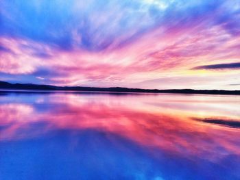 Scenic view of lake against dramatic sky during sunset