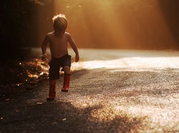 Rear view of boy running on road