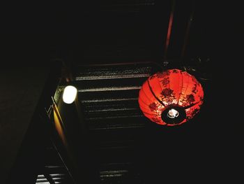 Low angle view of illuminated lighting equipment hanging at night