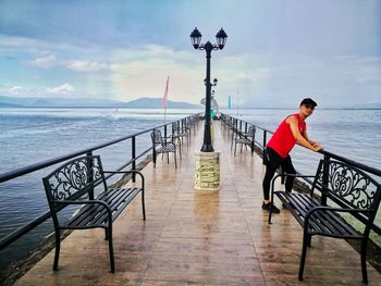 Man looking at pier on sea against sky