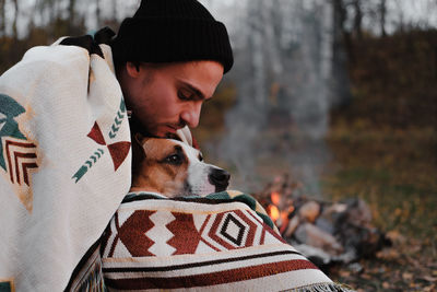 Midsection of man with dog wearing hat