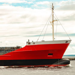 Red boat sailing in sea against sky