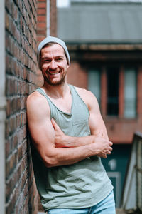 Portrait of smiling man standing against brick wall