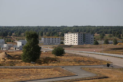 Road by buildings against clear sky