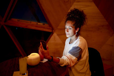 Woman using a mobile phone while relaxing in a dome tent.