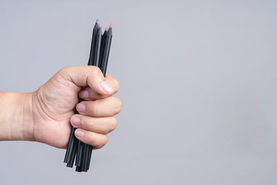 Close-up of hand holding metal against white background