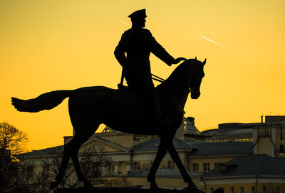 Silhouette georgy zhukov statue at manege square against clear sky during sunset