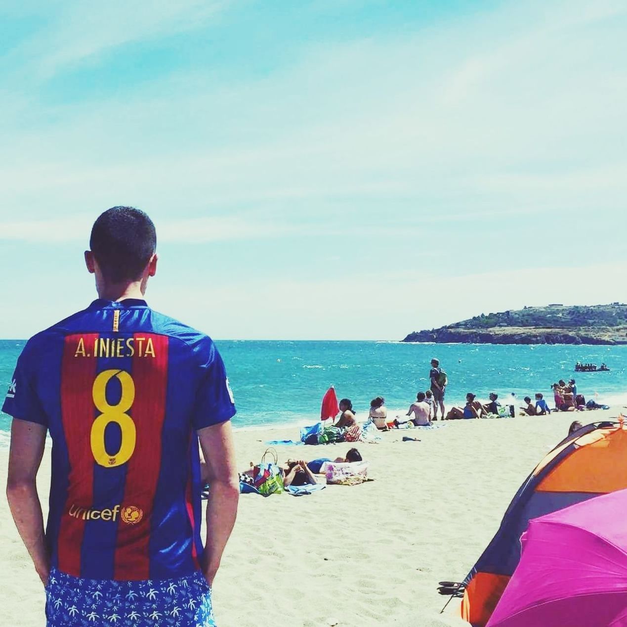 REAR VIEW OF PEOPLE STANDING AT BEACH