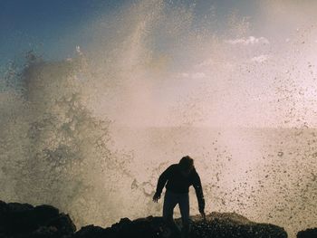 Silhouette man standing by sea against sky