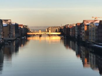 Buildings by river against sky in city