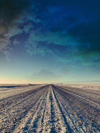 Scenic view of road amidst field against sky