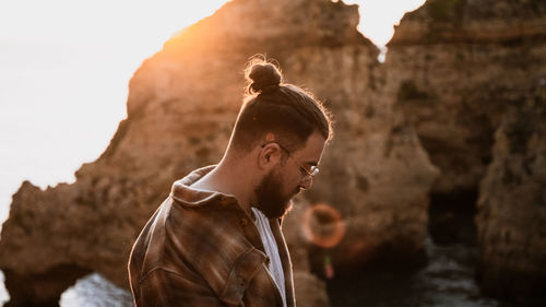 Man looking down agaisnt rock formation at sunrise