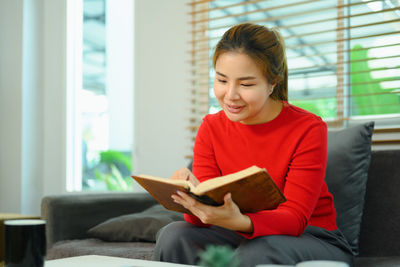 Young woman using digital tablet while sitting on sofa at home