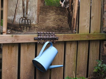 High angle view of blue watering can hanging from hook below painting on wall