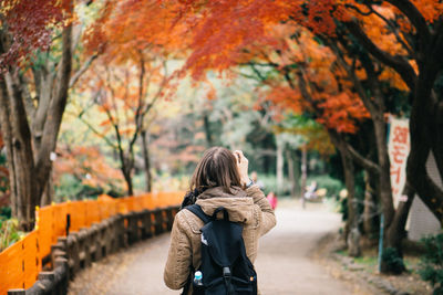 Rear view of woman on road during autumn