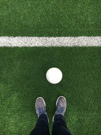 Low section of person standing in front of soccer ball at field
