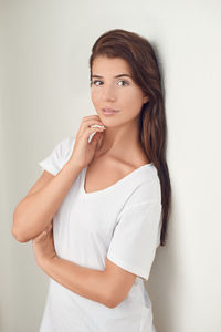 Portrait of young woman against white wall