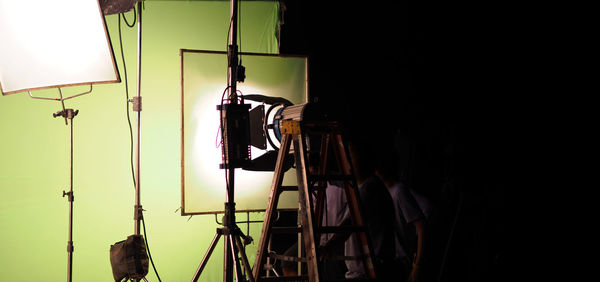 Low angle view of illuminated lighting equipment hanging against wall