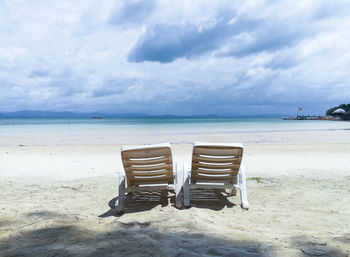 Chair on beach against sky