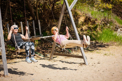 Two elderly women joyfully swinging on a swing