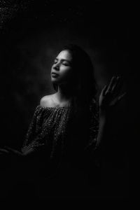 Close-up of young woman against black background