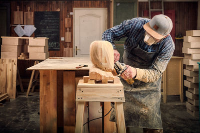 Experienced carpenter in work clothes and small buiness owner working in woodwork workshop