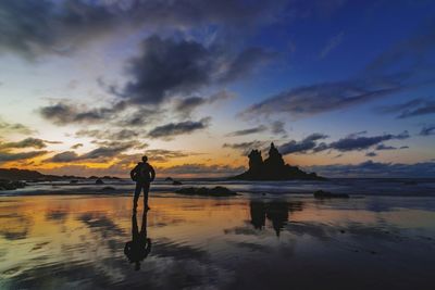 Silhouette man standing on beach against sky during sunset