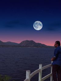 Full length of man standing in sea against sky at night