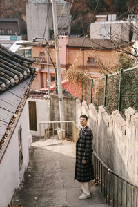 Portrait of young man standing against buildings in city