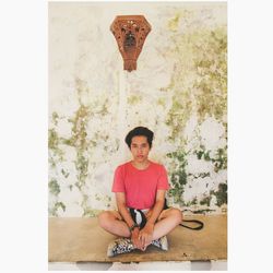 Portrait of young man sitting against wall