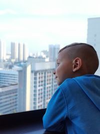 Portrait of boy looking through cityscape window