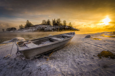 Boat at frozen lake at sunset