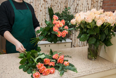 Midsection of man holding flower bouquet against wall