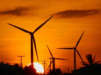 Silhouette windmills against sky during sunset