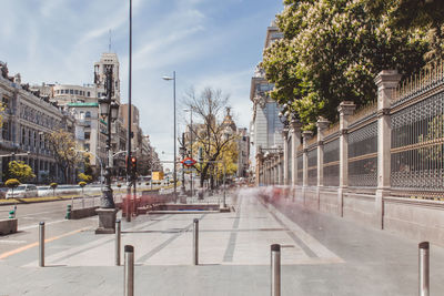 Road by buildings in city against sky