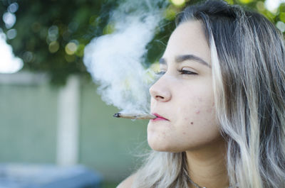 Portrait of young woman smoking outdoors