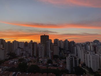 Modern buildings in city against sky during sunset