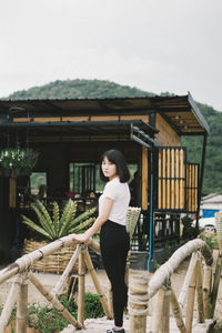 Portrait of young woman standing against railing