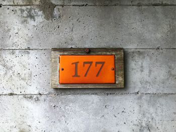 Number on orange placard against concrete wall