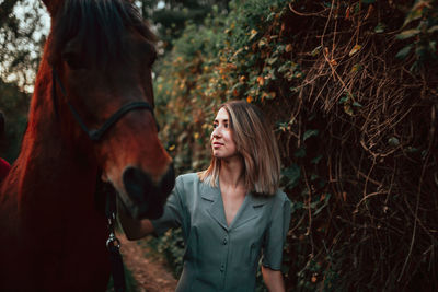 Young woman standing with horse outdoors